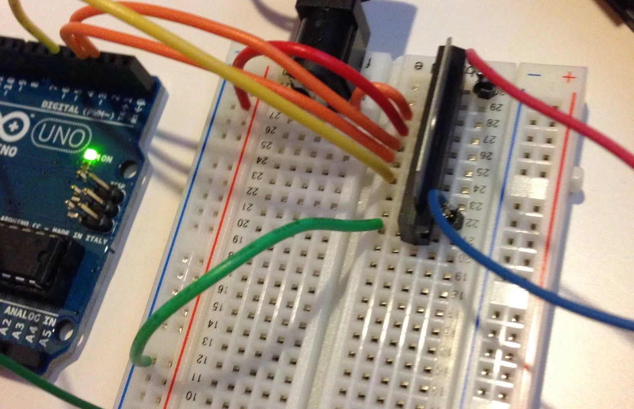 An Arduino Uno connected to a breadboard with jumper wires and a push button.